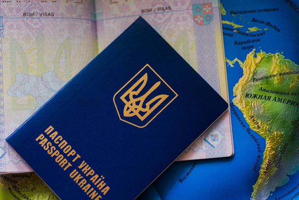 Uzavřený zahraniční pas Ukrajiny leží na otevřeném pasu a na mapě světa. Volný vstup Ukrajinců do Evropy. Cestovní pasy k odjezdu do Evropy bez víz. Bezvízový režim pro Ukrajinu. - Fotografie, Obrázek