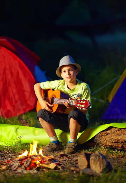 boy playing a guitar near bonfire, summer camp - Photo, Image