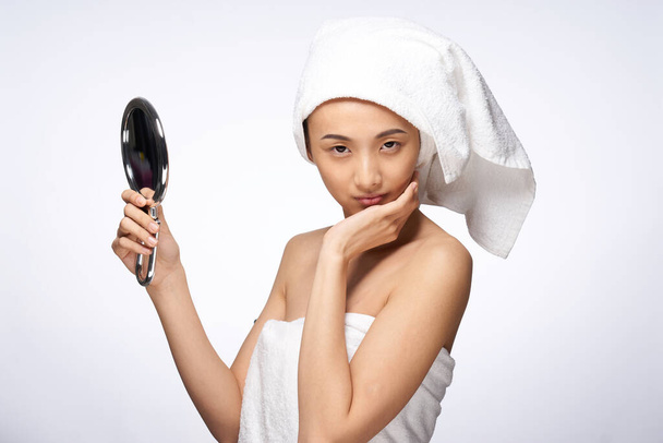 femme avec une serviette sur la tête tenant un miroir dans ses mains style de vie soins de la peau - Photo, image
