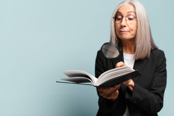 senior pretty woman with a book and a magnifying glass. search concept - Foto, Imagen