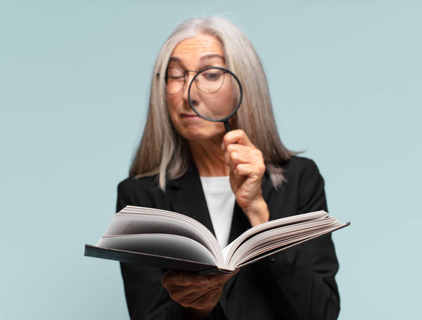 senior pretty woman with a book and a magnifying glass. search concept - Фото, зображення