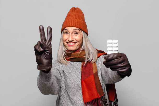 senior pretty woman with a pills tablet wearing winter clothes. flu concept - Photo, Image