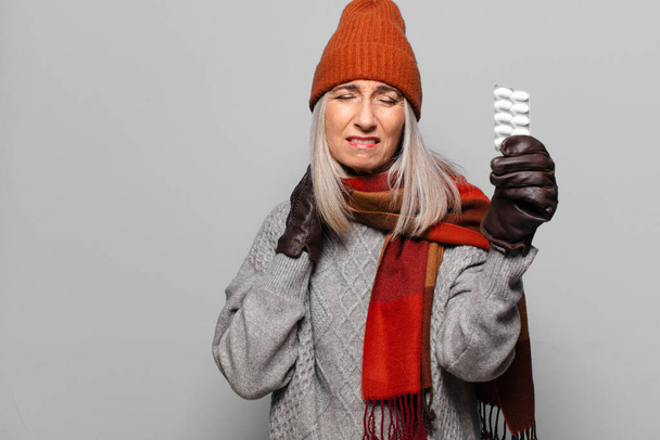 senior pretty woman with a pills tablet wearing winter clothes. flu concept - Photo, image