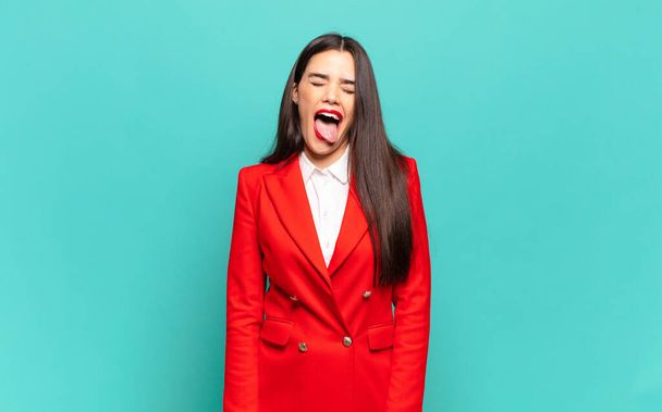 young pretty woman with cheerful, carefree, rebellious attitude, joking and sticking tongue out, having fun. business concept - Foto, Imagen