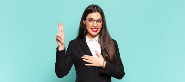 young pretty woman looking happy, confident and trustworthy, smiling and showing victory sign, with a positive attitude. business concept - Fotoğraf, Görsel
