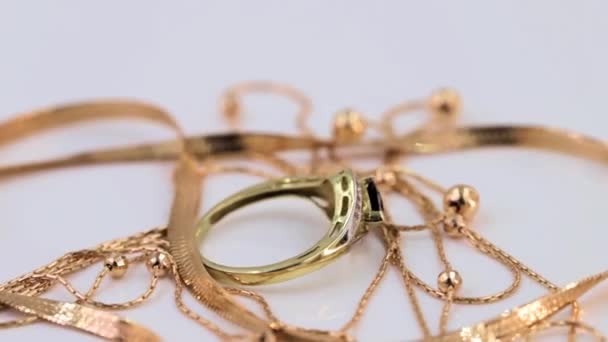 Arany gyűrűk, fülbevalók és láncok forognak a tengelyük körüli állványon - Felvétel, videó