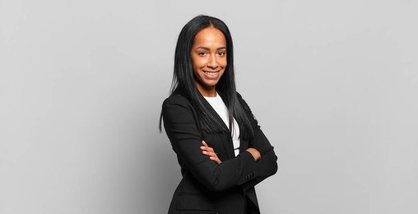 young black woman smiling to camera with crossed arms and a happy, confident, satisfied expression, lateral view. business concept - Φωτογραφία, εικόνα