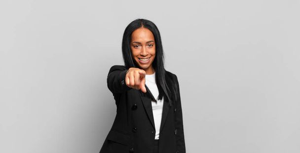 young black woman pointing at camera with a satisfied, confident, friendly smile, choosing you. business concept - Foto, afbeelding