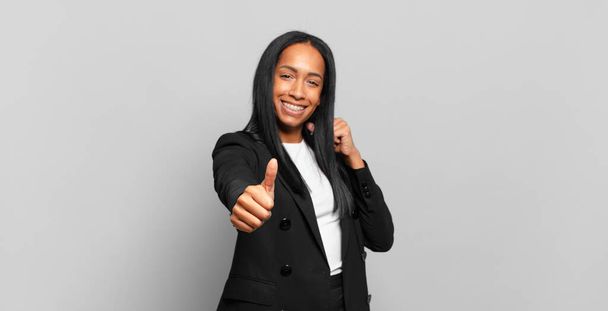 young black woman feeling proud, carefree, confident and happy, smiling positively with thumbs up. business concept - Fotografie, Obrázek