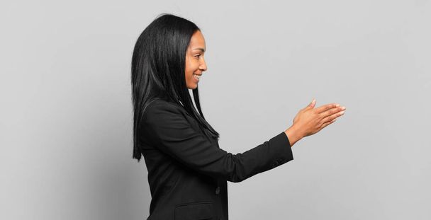 young black woman smiling, greeting you and offering a hand shake to close a successful deal, cooperation concept. business concept - Fotografie, Obrázek