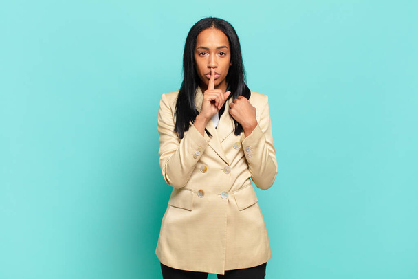 young black woman looking serious and cross with finger pressed to lips demanding silence or quiet, keeping a secret. business concept - Photo, image