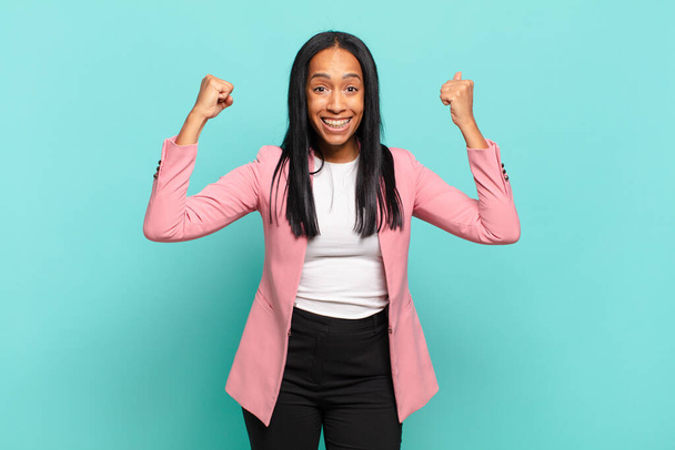 молодая черная женщина празднует невероятный успех, как победитель, глядя взволнованный и счастливый говоря взять это!. бизнес концепция - Фото, изображение