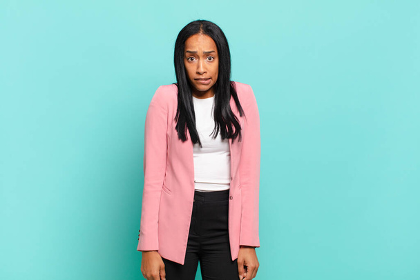 young black woman looking puzzled and confused, biting lip with a nervous gesture, not knowing the answer to the problem. business concept - Valokuva, kuva