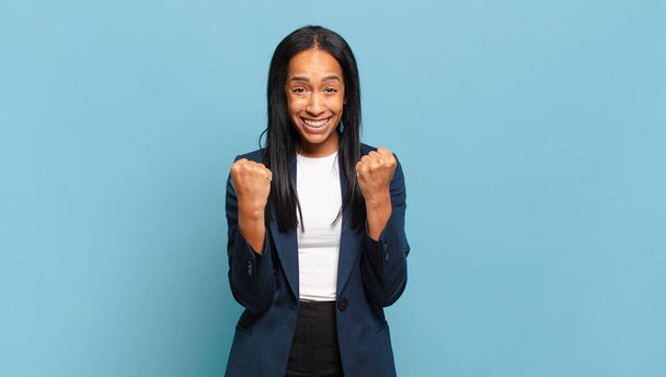 jeune femme noire criant triomphalement, riant et se sentant heureuse et excitée tout en célébrant le succès. concept d'entreprise - Photo, image