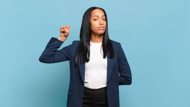 若い黒人女性は深刻さを感じ、強く反抗的で、拳を上げ、革命のために抗議したり戦う。ビジネスコンセプト - 写真・画像