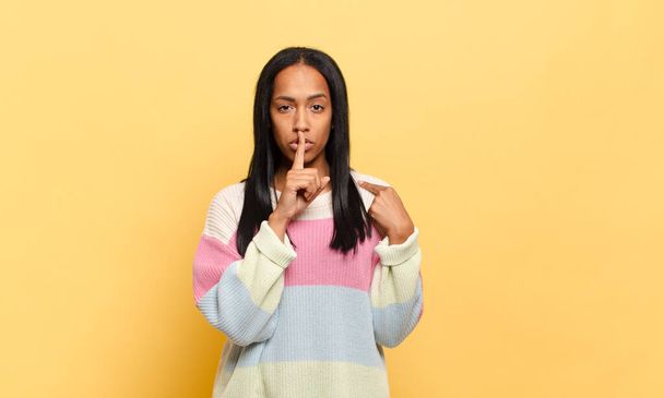 young black woman looking serious and cross with finger pressed to lips demanding silence or quiet, keeping a secret - Photo, Image