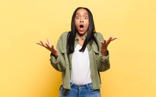 young black woman feeling extremely shocked and surprised, anxious and panicking, with a stressed and horrified look - Foto, imagen