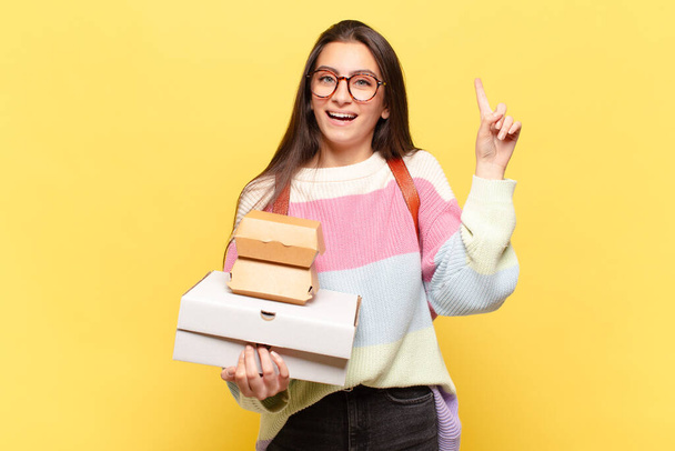 young pretty woman feeling like a happy and excited genius after realizing an idea, cheerfully raising finger, eureka!. take aeay fast food concept - Photo, Image