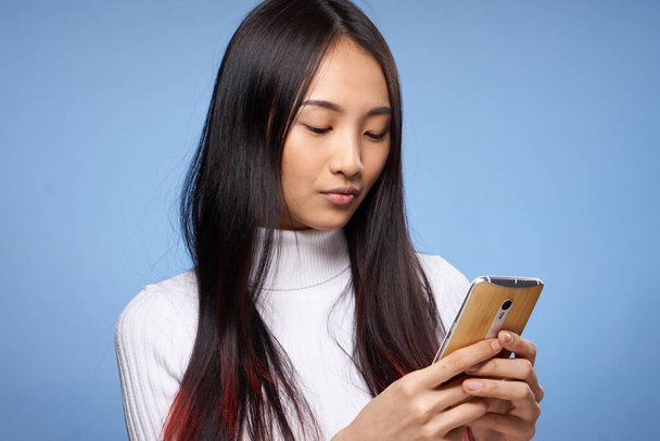 mulher de aparência asiática com um telefone em mãos internet tecnologia comunicação close-up - Foto, Imagem