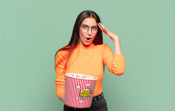 young pretty woman looking happy, astonished and surprised, smiling and realizing amazing and incredible good news. pop corns concept - Photo, Image