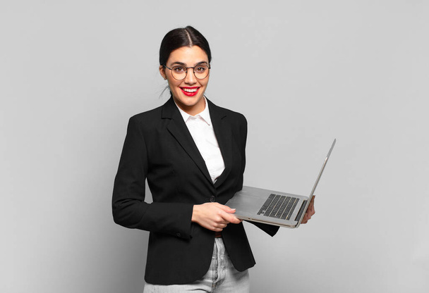 young pretty woman looking happy and pleasantly surprised, excited with a fascinated and shocked expression. laptop concept - Zdjęcie, obraz