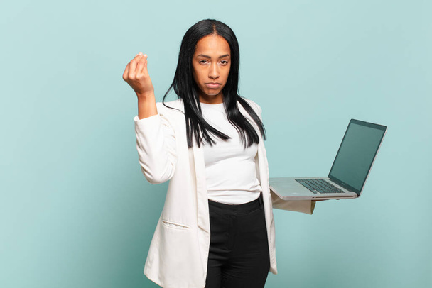 young black woman making capice or money gesture, telling you to pay your debts!. laptop concept - Zdjęcie, obraz
