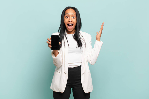 young black woman feeling happy, surprised and cheerful, smiling with positive attitude, realizing a solution or idea. smart phone concept - Foto, Imagem
