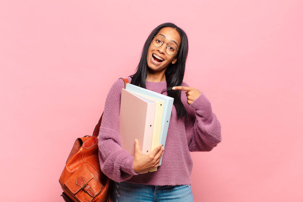 young black woman looking excited and surprised pointing to the side and upwards to copy space. student concept - Photo, Image
