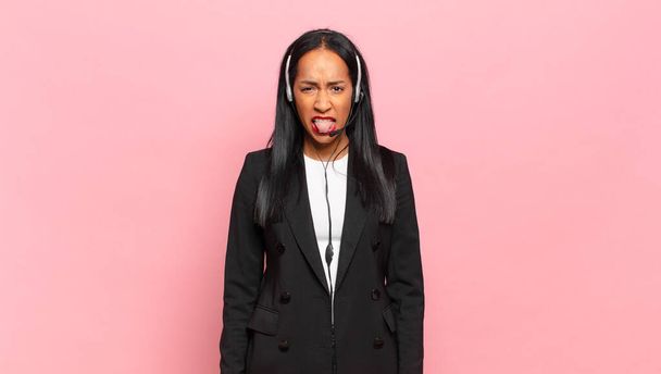 young black woman feeling disgusted and irritated, sticking tongue out, disliking something nasty and yucky. telemarketing concept - Foto, imagen