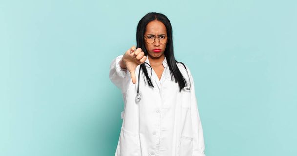 young black woman feeling cross, angry, annoyed, disappointed or displeased, showing thumbs down with a serious look. physician concept - Photo, Image