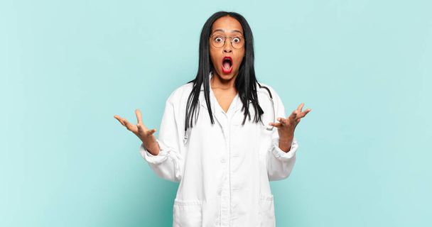young black woman open-mouthed and amazed, shocked and astonished with an unbelievable surprise. physician concept - Foto, Bild