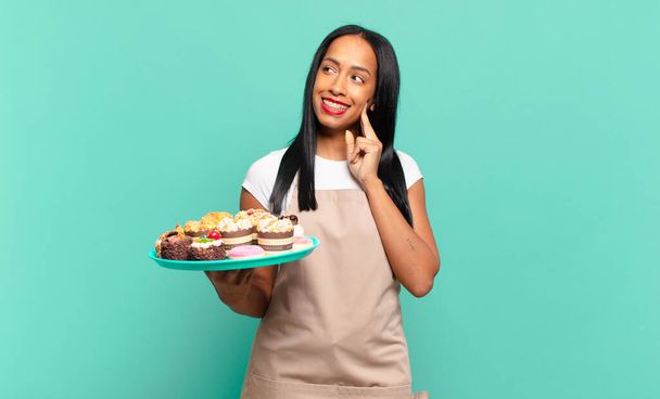 young black woman smiling happily and daydreaming or doubting, looking to the side. bakery chef concept - Photo, image