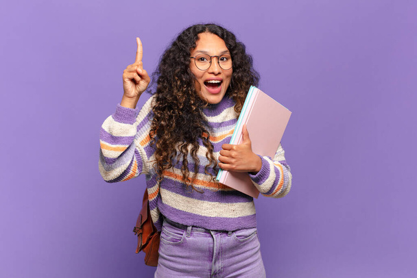 young hispanic woman feeling like a happy and excited genius after realizing an idea, cheerfully raising finger, eureka!. student concept - Foto, Imagen