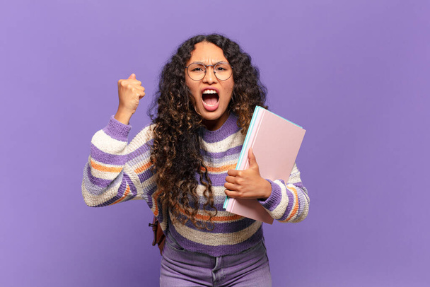 young hispanic woman shouting aggressively with an angry expression or with fists clenched celebrating success. student concept - Photo, image