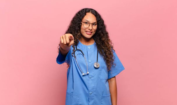 young hispanic woman pointing at camera with a satisfied, confident, friendly smile, choosing you. nurse concept - Φωτογραφία, εικόνα