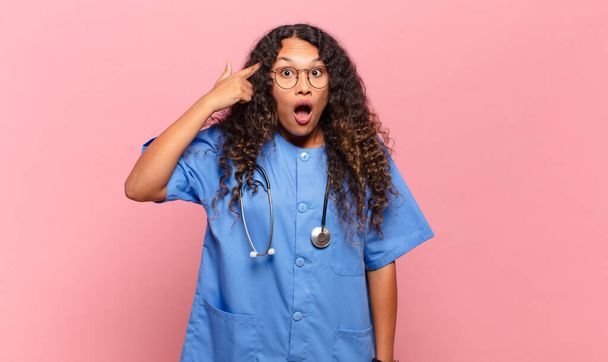 young hispanic woman looking surprised, open-mouthed, shocked, realizing a new thought, idea or concept. nurse concept - Zdjęcie, obraz