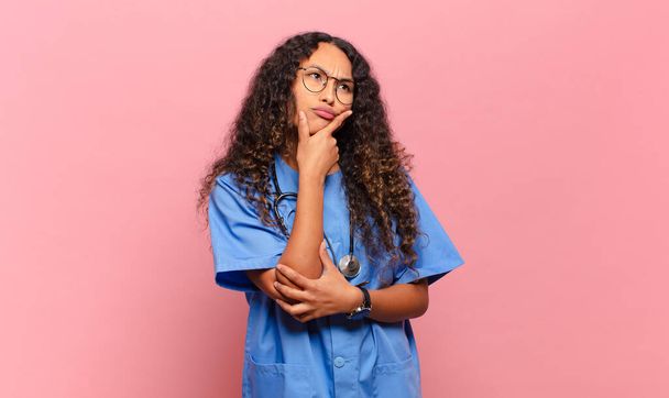 若いヒスパニック系の女性の思考、疑問や混乱を感じ、さまざまなオプションで、どの決定をするか疑問に思います。看護師の概念 - 写真・画像