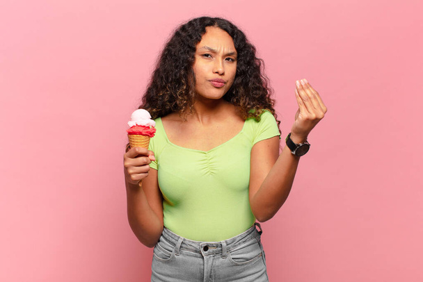 young hispanic woman making capice or money gesture, telling you to pay your debts!. ice cream concept - Zdjęcie, obraz
