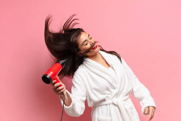 young pretty hispanic woman. happy and surprised expression. hair dryer concept - Foto, immagini