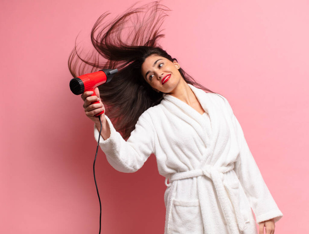 young pretty hispanic woman. happy and surprised expression. hair dryer concept - Zdjęcie, obraz