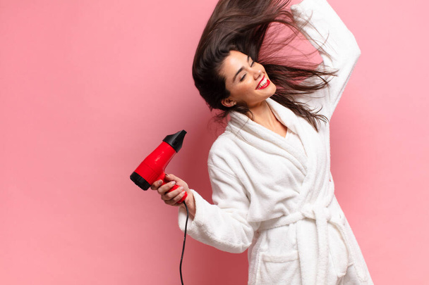 young pretty hispanic woman. happy and surprised expression. hair dryer concept - Фото, зображення