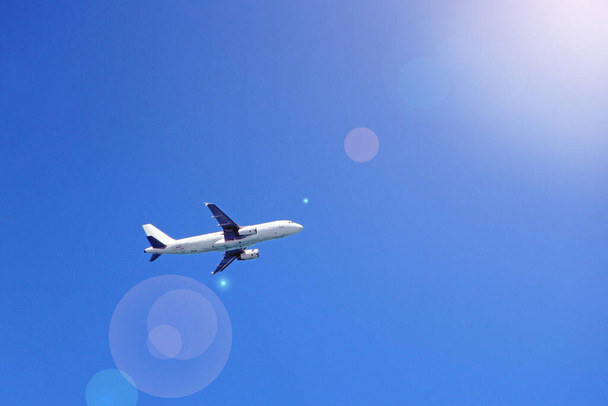 Plane flying high in sky. View to air liner flying in blue sky. Airplane seen in blue sky. Aerial panorama with aircraft in cloudless sky. Flying air liner in sunny rays - Photo, Image