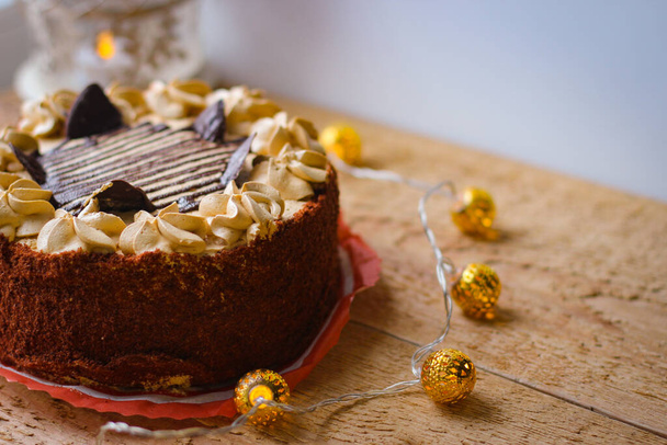 Πεντανόστιμο κέικ σοκολάτας καλυμμένο με κομμάτια σοκολάτας και γαρνιρισμένο με μια βουτυρόκρεμα διακόσμηση - Φωτογραφία, εικόνα