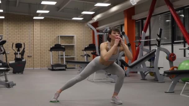 Sportowa kobieta rozgrzewająca się i trenująca na siłowni - Materiał filmowy, wideo