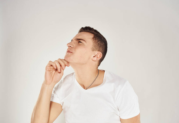 Retrato de un hombre pensativo con una camiseta blanca vista lateral fondo claro - Foto, imagen