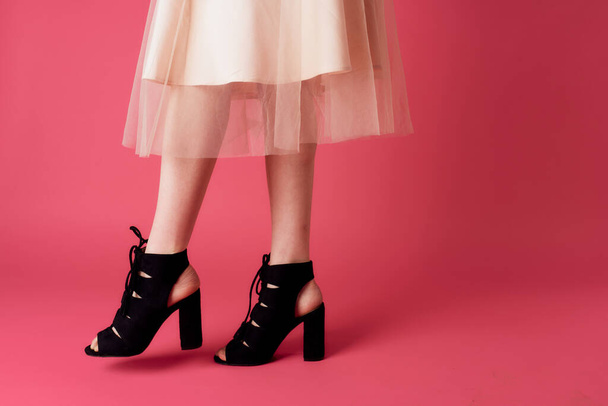 Female feet black fashionable heels shoes charm pink background - Fotoğraf, Görsel