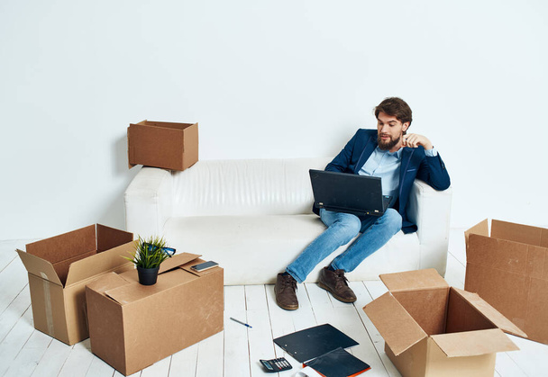 Hombre sentado en cajas de sofá con cosas nuevo lugar de trabajo oficina profesional - Foto, Imagen