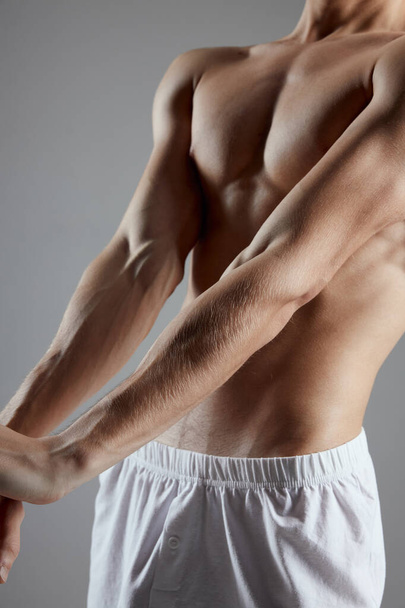Sportler mit gepumpten Muskeln Armpresse beschnitten Ansicht grauer Hintergrund - Foto, Bild