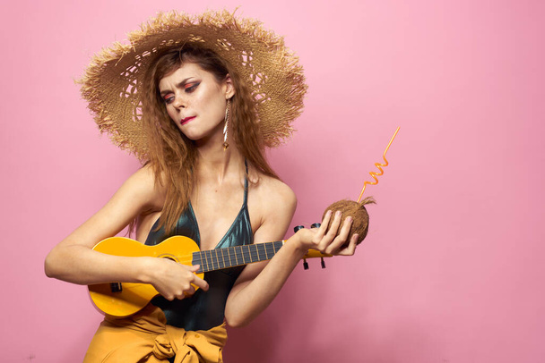 Pretty woman wearing straw hat ukulele holding pink background lifestyle - Foto, Imagen