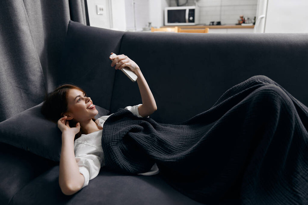 femme heureuse avec un téléphone portable devant ses yeux se trouve sur un canapé doux confortable - Photo, image